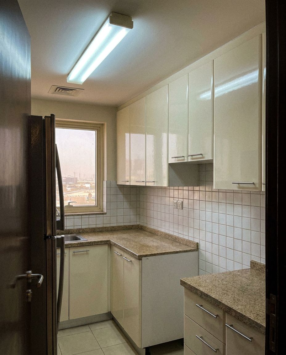 Apartment kitchen before: white gloss cabinets, beige granite worktop and a strip light